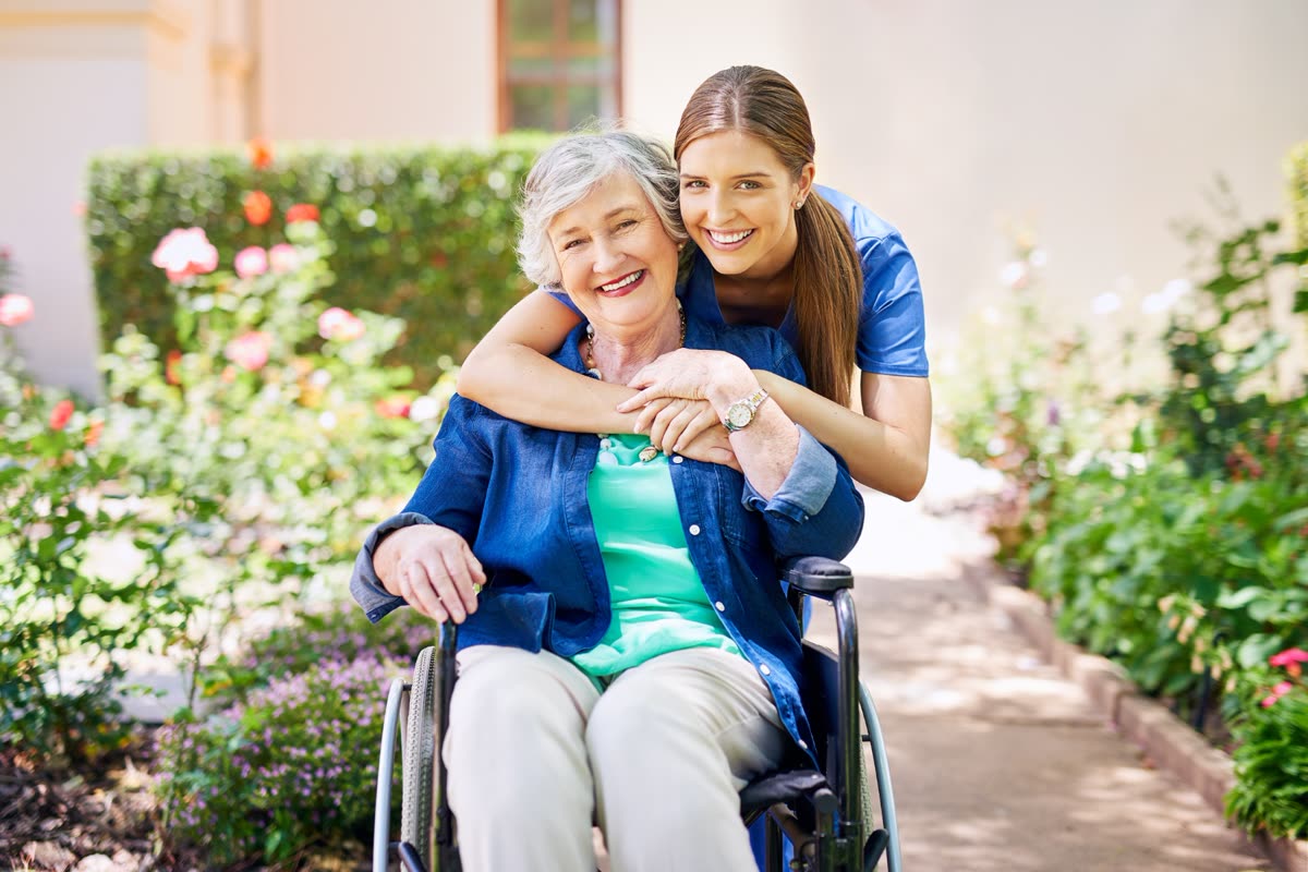A caregiver embracing a smiling resident in a care home garden